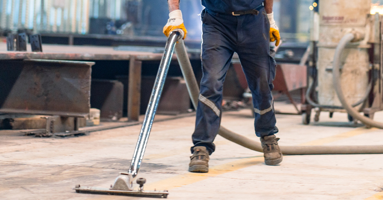 A person using industrial cleaning equipment in a factory setting.