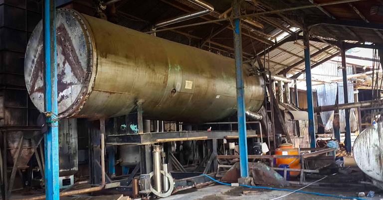 Large industrial tank inside a factory with metal support beams.