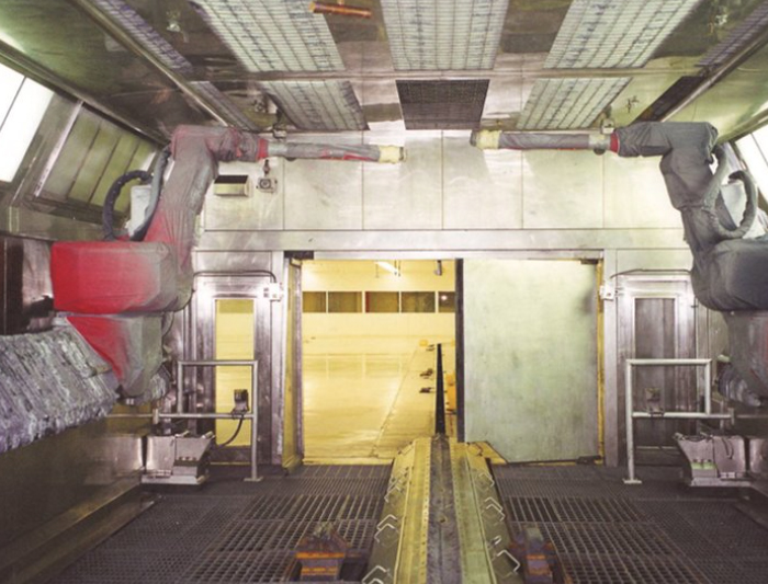 Industrial robotic arms in a factory setting spraying materials.