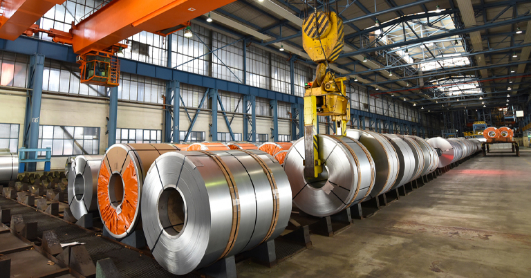 Steel coils in a factory warehouse with overhead crane and industrial setting.