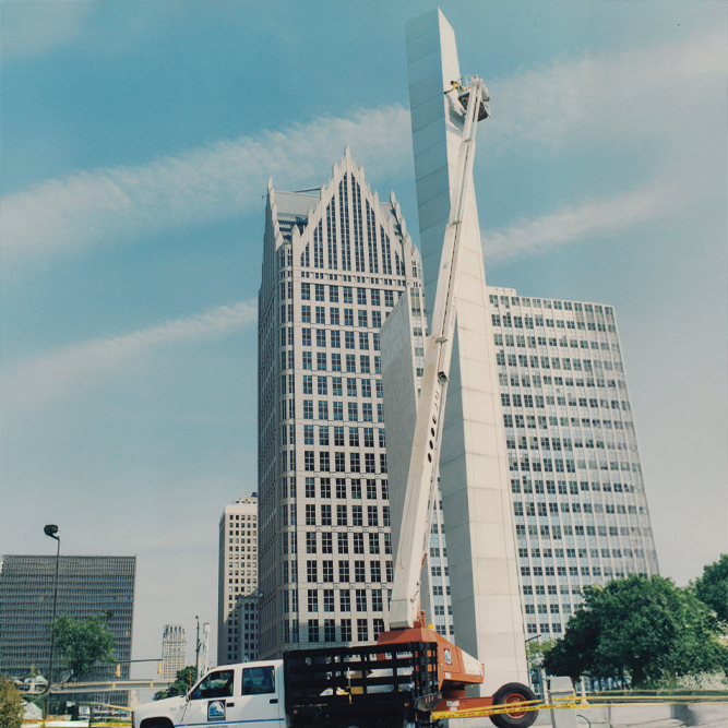 Crane lift near tall buildings in urban cityscape under clear sky.