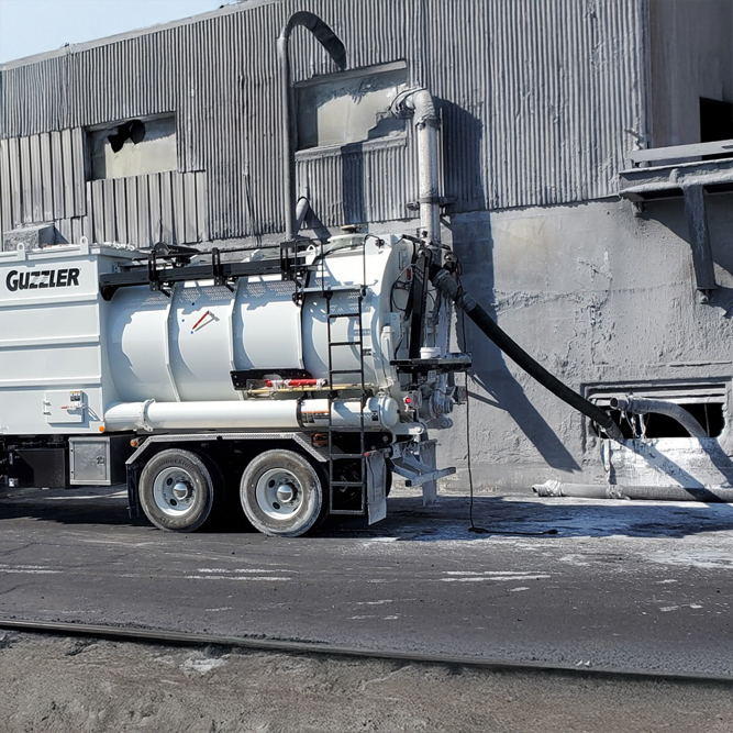 Industrial vacuum truck performing facility maintenance tasks.