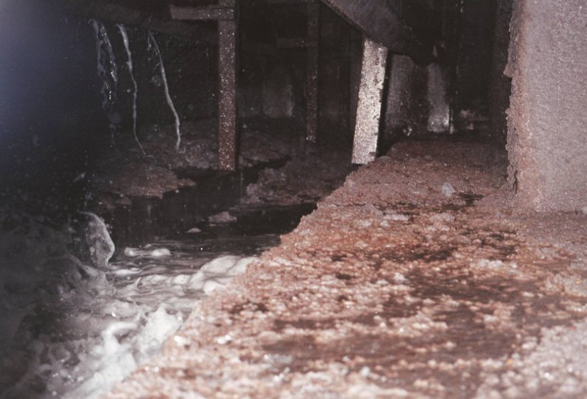 Corroded metal and water leakage in a damaged industrial setting.